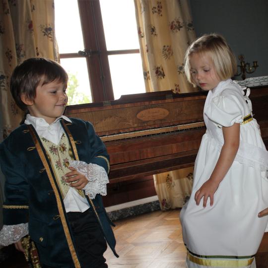 Enfants en costume devant le piano du salon de musique