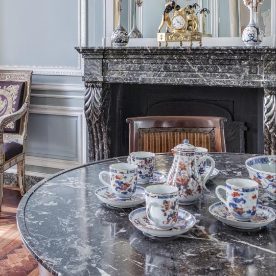 Grand salon de la Maison de l'armateur présentant un service à café en porcelaine.