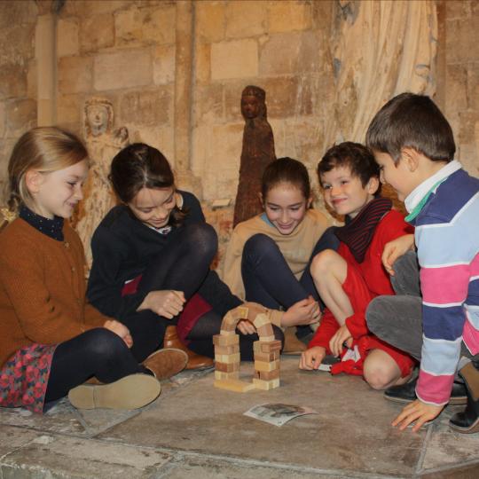 Un groupe d'enfants construit une petite voûte romane en bois.
