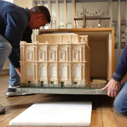 La maquette est portée dans la caisse de stockage, recouverte de mousse à l'intérieur.