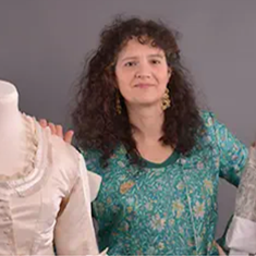 Photographie de madame Haran encadrée par deux costumes sur mannequin.