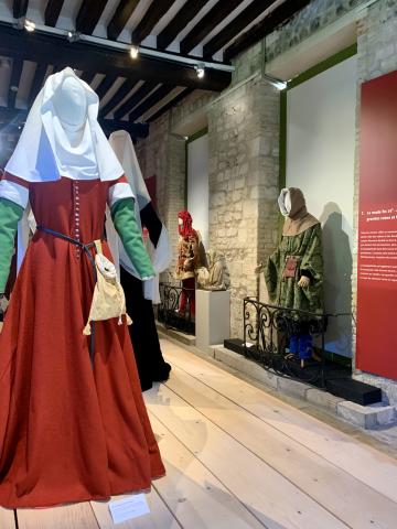 Photographie de l'exposition présentant en costume féminin, une cotte rouge du 14eme siècle.