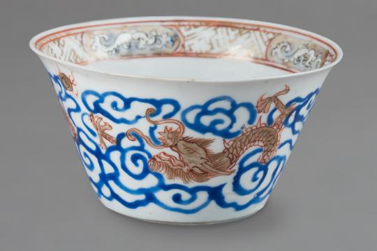 Petit bol en porcelaine présentant un dragon doré dans un décor bleu.
