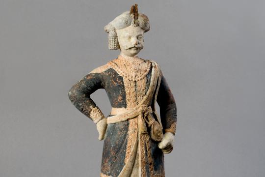 Personnage masculin, dans un costume oriental noir et orangé et portant un turban sur la tête.