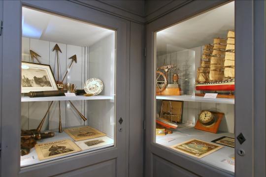Vitrine sur la chasse à la baleine (harpons, fanons, vue de baleinière) et maquette de bateau.