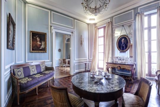 Grand salon présentant un parquet en bois exotique et du mobilier d'époque Empire.