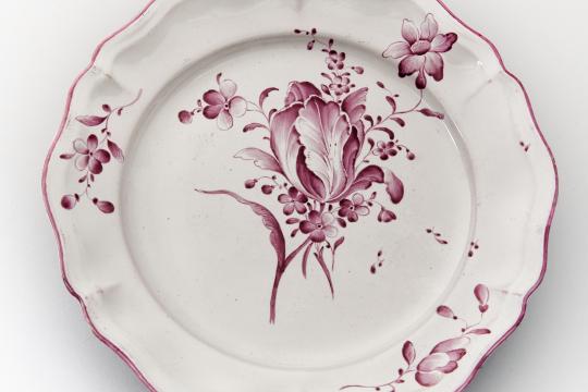 Assiette en faïence blanche de Strasbourg aux bords chantournés, présentant un décor floral rose.