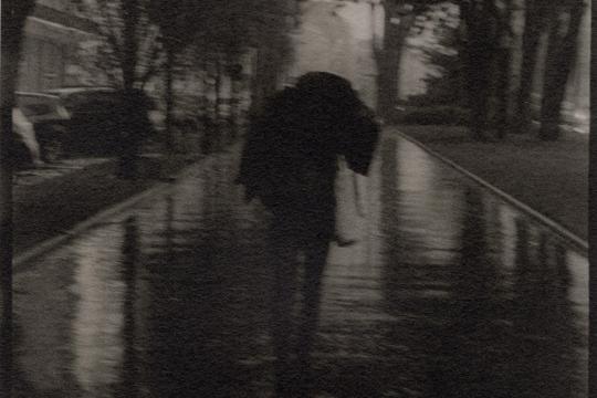 Photographie en noir et blanc d'un personnage sous la pluie