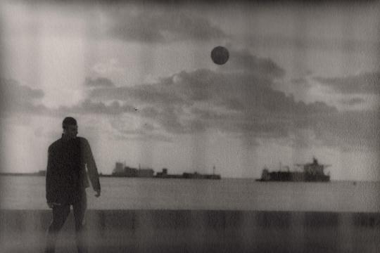Photographie noir et blanc, un homme regarde des navires au bord du quai