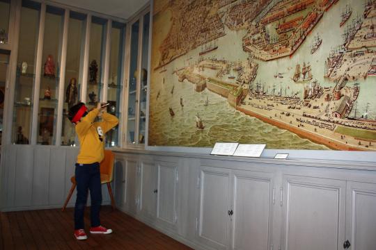 Un enfant observe à la longue vue les détails d'un plan de la ville et du port du Havre.