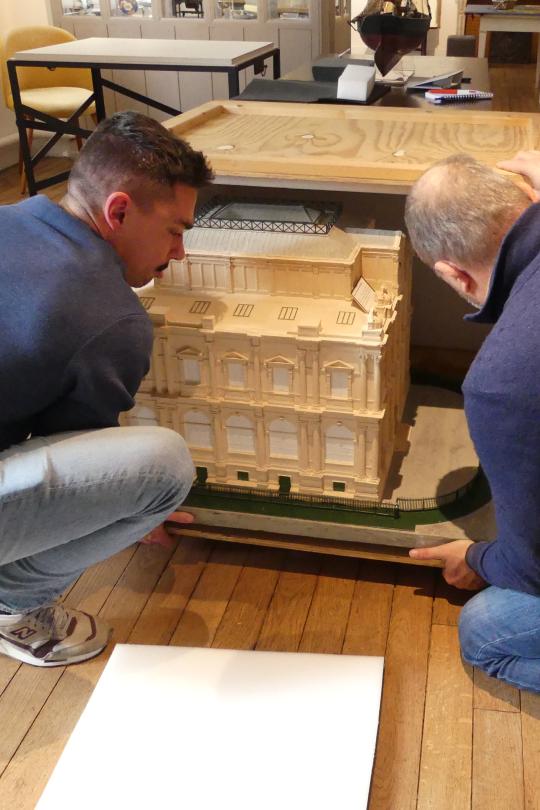 Deux agents mettent la maquette du musée des beaux-arts dans une caisse de stockage et de transport en vue du démontage des collections du musée.